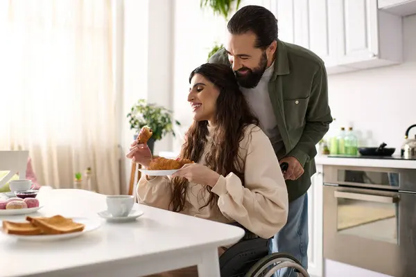 Cheerful man having great time at breakfast with his beautiful disabled wife that eating croissant — Stock Photo