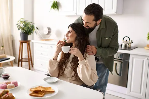 Barbuto amorevole marito abbracciando la sua bella moglie disabile durante la colazione in cucina a casa — Foto stock