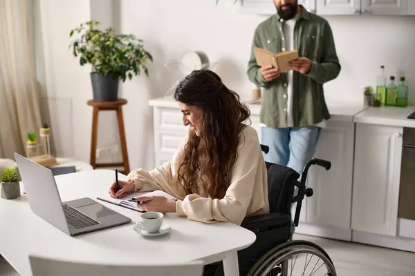 Joyous woman with mobility disability working from home next to her bearded hasband reading book — Stock Photo