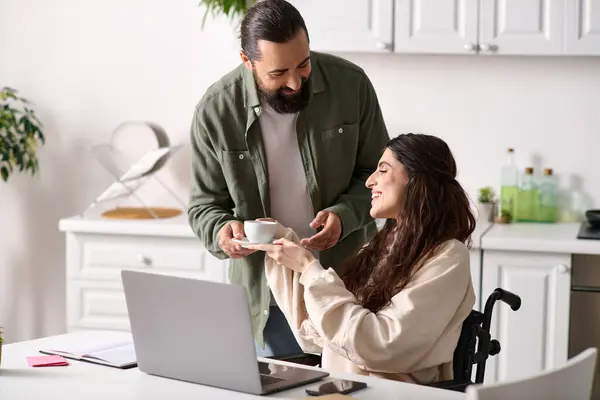 Handsome man in homewear offering coffee to his disabled hard working beautiful wife in wheelchair — Stock Photo