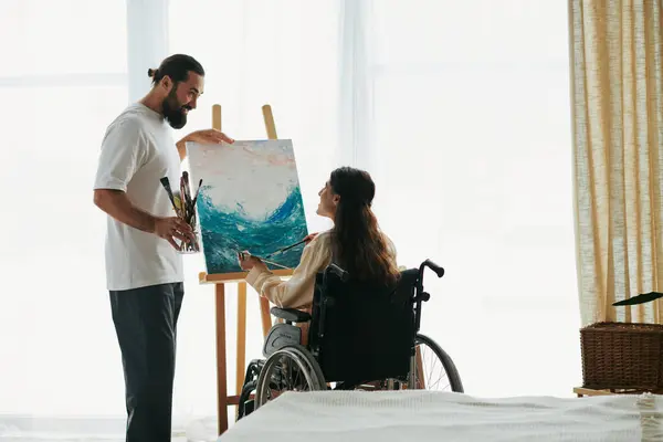 Attractive cheerful couple of bearded man and disabled woman painting on easel together at home — Stock Photo