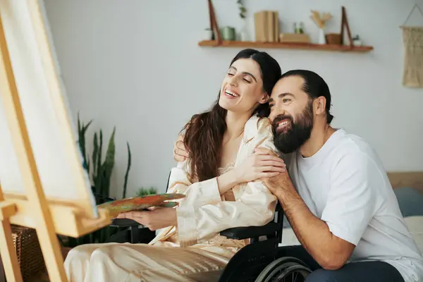 Appealing cheerful couple of bearded man and disabled woman painting on easel together at home — Stock Photo