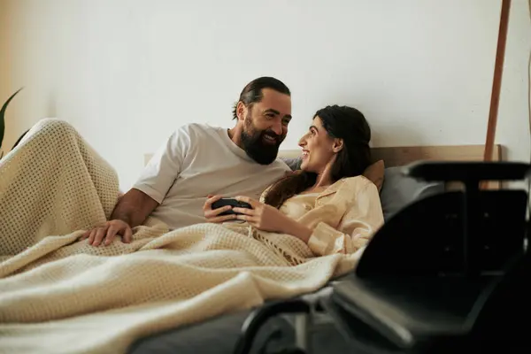 Schöne, fröhliche Frau mit Gehbehinderung, die neben ihrem bärtigen, liebevollen Ehemann im Bett liegt — Stockfoto