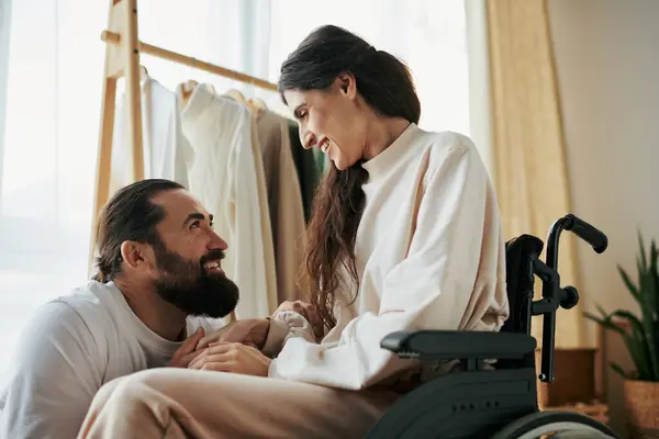 Привлекательный веселый мужчина проводит время со своей красивой женой-инвалидом в спальне дома — стоковое фото