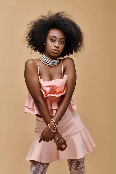 Young dark skinned model with curly hair posing in pastel peach ruffled top on beige background — Stock Photo