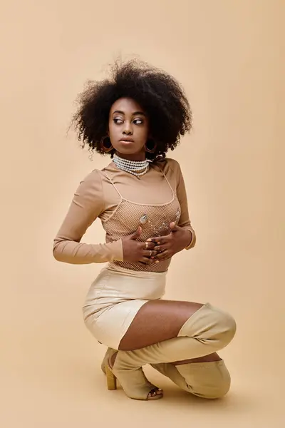 Confident african american model in stylish outfit and thigh-high boots posing on beige backdrop — Stock Photo
