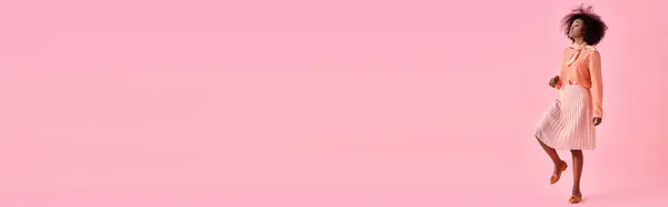 Ricci donna afroamericana in camicetta color pesca e gonna midi in posa su sfondo rosa pastello, banner — Foto stock