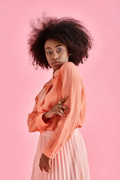 Confident african american woman in peach blouse, midi skirt and neck scarf posing on pink backdrop — Stock Photo