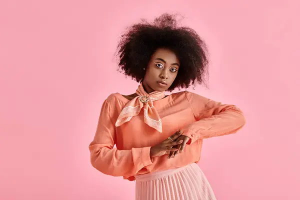 Pretty african american woman in peach blouse, midi skirt and neck scarf posing on pink backdrop — Stock Photo