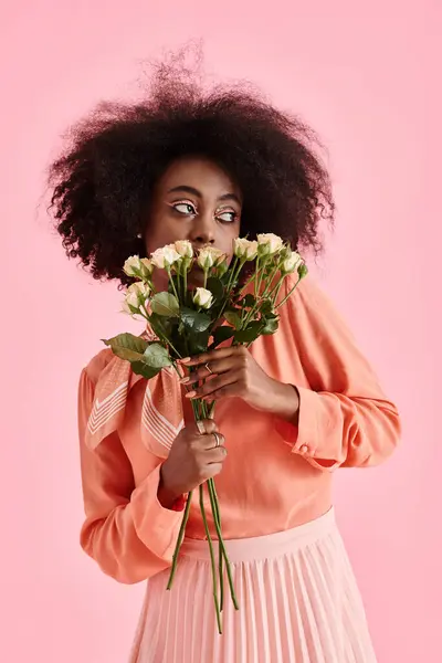 Африканская американка в персиковой пушистой блузке с цветами и отводящей взгляд на розовый фон — стоковое фото