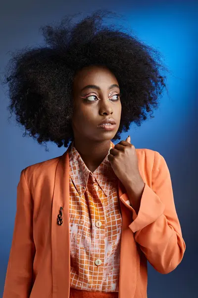 Rizado joven africana americana mujer en melocotón fuzz chaqueta mirando hacia otro lado en gradiente azul telón de fondo - foto de stock
