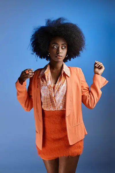Lockige afrikanisch-amerikanische Frau im pfirsichfarbenen Fuzz-Outfit mit Blazer auf blauem Hintergrund — Stockfoto