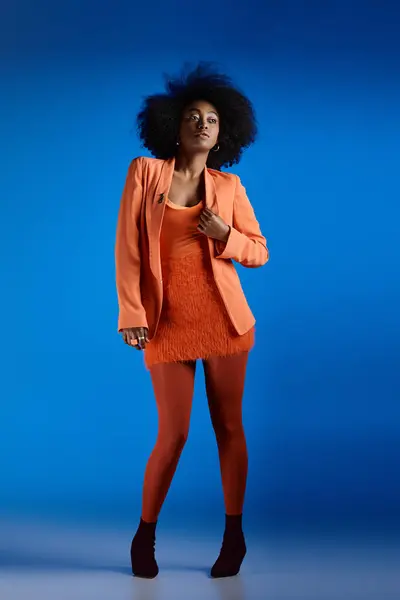 Pretty african american woman in textured dress and blazer posing on high heels, vivid blue backdrop — Stock Photo