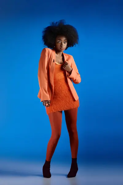 Bella ragazza afroamericana in abito strutturato e blazer posa sui tacchi alti, vivido sfondo blu — Foto stock