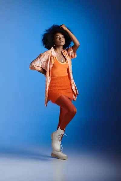 Elegante donna afroamericana in camicia fantasia e abito strutturato in posa su sfondo blu — Foto stock