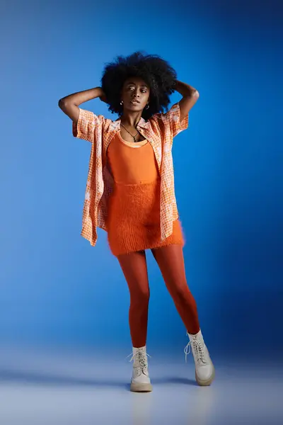 Fashionable african american model in patterned shirt and stylish dress posing on blue backdrop — Stock Photo