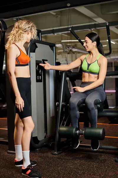 Energische Trainerin berät ihren blonden, gut gelaunten Kunden im Fitnessstudio in der Nähe der Schulterpresse — Stockfoto