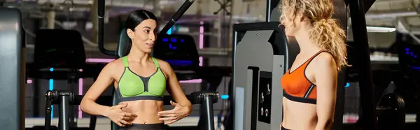 Energische Trainerin berät ihre freudige Klientin im Fitnessstudio in der Nähe der Schulterpresse, Banner — Stockfoto
