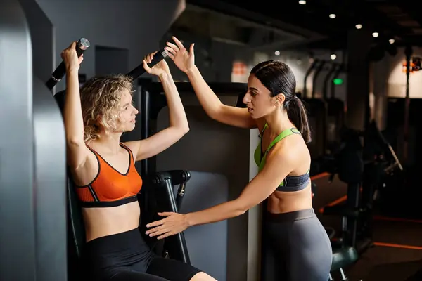 Starke weibliche Trainerin berät ihre attraktive, freudige Kundin im Fitnessstudio in der Nähe der Schulterpresse — Stockfoto