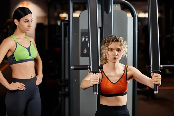 Atractiva mujer entrenador explicando a su atractivo cliente alegre cómo utilizar la máquina de prensa de pecho - foto de stock