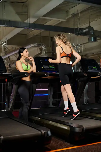 Positive appealing female coach and her client in sportwear exercising actively on treadmill in gym — Stock Photo