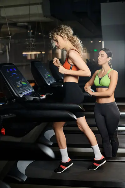 Добре виглядає спортивний жіночий тренер і її блондинка клієнт в спортивному одязі вправи на біговій доріжці в спортзалі — стокове фото
