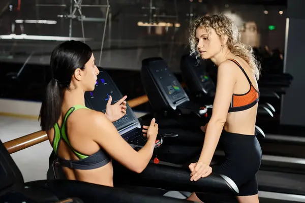 Good looking sporty female coach and her blonde client in sportwear exercising on treadmill in gym — Stock Photo