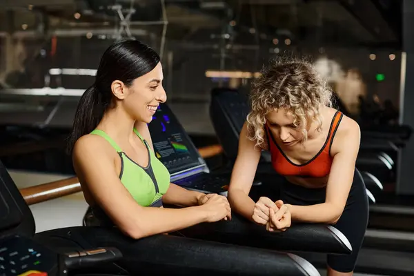 Alegre atraente treinador feminino e seu cliente em sportwear exercitando-se ativamente na esteira na academia — Fotografia de Stock
