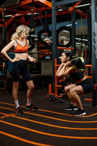 Gut aussehende sportliche Frau und ihre athletische Trainerin beim Training mit Powerbag im Fitnessstudio — Stockfoto