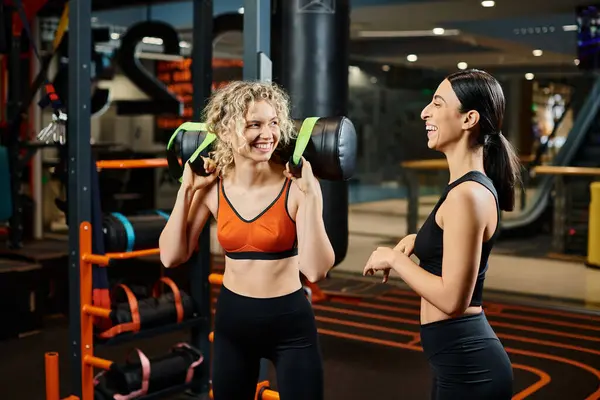 Joyous appealing woman and her athletic female coach practicing with power bag while in gym — Stock Photo