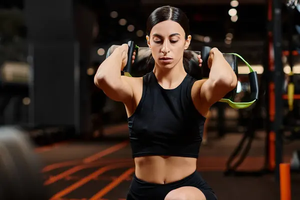 Atraente mulher atlética com cabelo morena em sportwear exercitando-se ativamente com saco de poder no ginásio — Fotografia de Stock