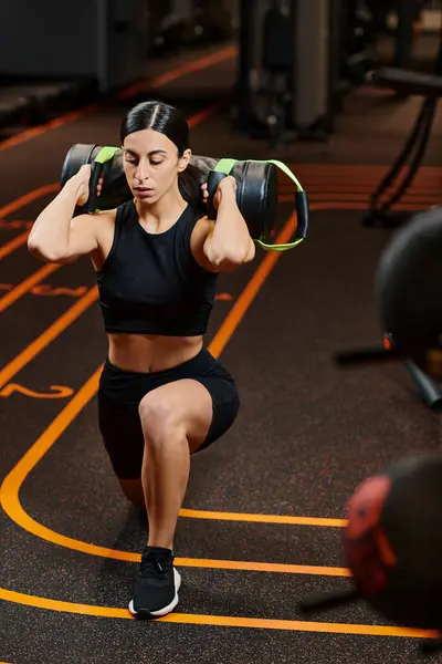Atraente mulher atlética com cabelo morena em sportwear exercitando-se ativamente com saco de poder no ginásio — Fotografia de Stock