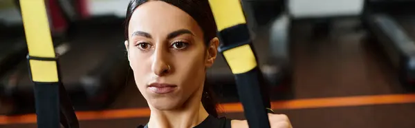 Mulher enérgica com cabelo morena em roupas esportivas confortáveis usando equipamentos pull ups no ginásio, banner — Fotografia de Stock