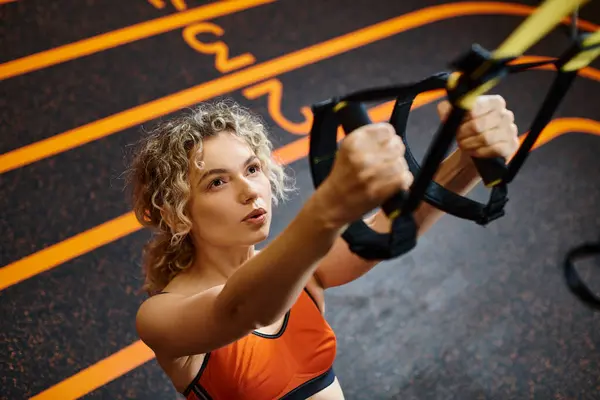 Mulher loira atraente em sportwear confortável exercitando com puxar equipamentos enquanto no ginásio — Fotografia de Stock