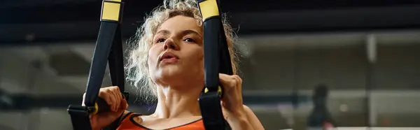 Good looking woman in comfortable sportwear exercising with pull ups equipment while in gym, banner — Stock Photo