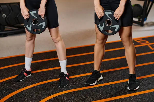 Abgeschnittene Ansicht athletischer Frauen in kuscheliger Sportbekleidung, die im Fitnessstudio aktiv mit Hantelscheiben hocken — Stockfoto