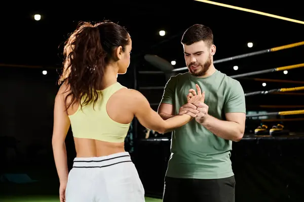 Un entraîneur masculin enseigne des techniques d'auto-défense à une femme dans une salle de gym. — Photo de stock