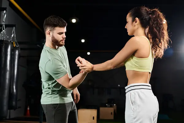 A male trainer teaches self-defense techniques to a woman, their movements flowing in harmony on the gym floor. — Stock Photo