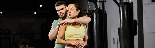 A male trainer is teaching self-defense techniques to a woman in a gym, demonstrating solidarity and empowerment. — Stock Photo