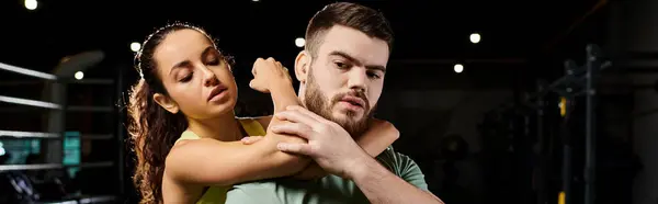 A male trainer demonstrates self-defense techniques to a woman in a gym, showcasing strength and coordination. — Stock Photo