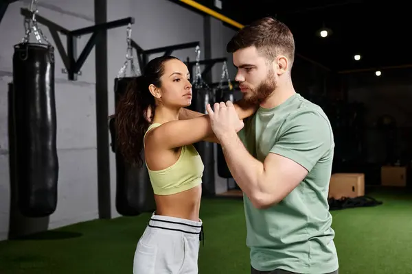 A male trainer guiding a woman through self-defense techniques in a gym. — Stock Photo