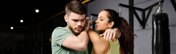 A male trainer is teaching self-defense techniques to a woman in a gym. — Stock Photo