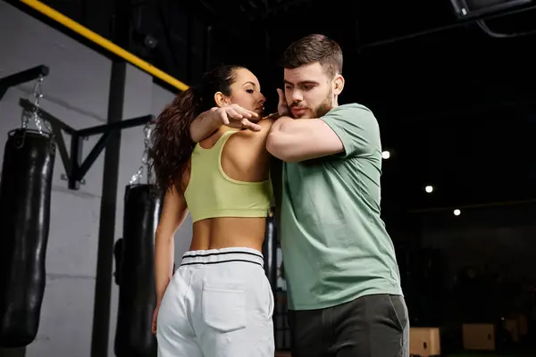 Entraîneur masculin démontre des techniques d'auto-défense à une cliente dans un cadre de gym. — Photo de stock