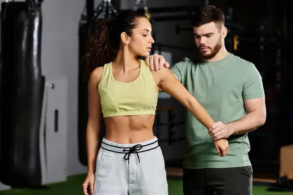 Ein männlicher Trainer demonstriert einer Frau in einem Fitnessstudio Selbstverteidigungstechniken und zeigt Einheit und Stärkung durch Fitness. — Stockfoto