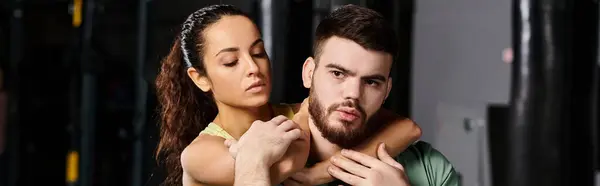 A male trainer holds a woman in his arms, demonstrating self-defense techniques in a gym setting. — Stock Photo