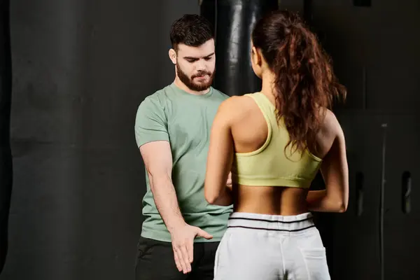 Un entrenador masculino demuestra técnicas de autodefensa a una mujer en un entorno de gimnasio. - foto de stock