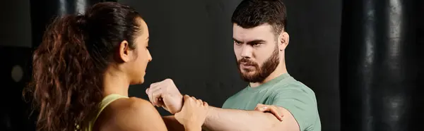 Un allenatore di sesso maschile che dimostra tecniche di autodifesa a una donna in palestra. — Foto stock
