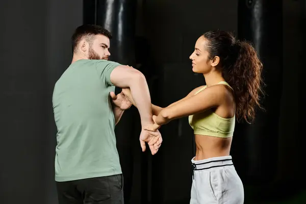 Un entrenador masculino enseña técnicas de autodefensa a una mujer en un gimnasio, demostrando fuerza, apoyo y unidad. - foto de stock