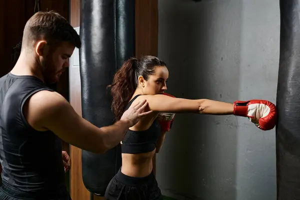 A male trainer guides a brunette sportswoman as they engage in boxing training in a gym, showcasing strength and skill. — Stock Photo