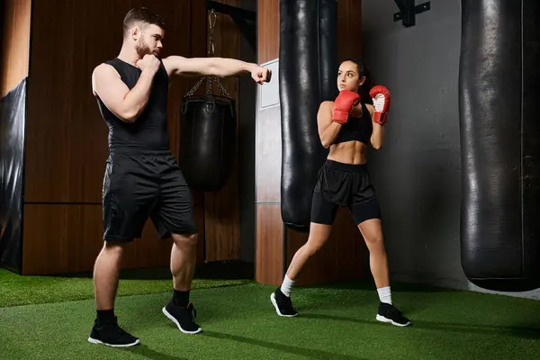 A male trainer guides a brunette sportswoman in active wear as they spar in a boxing ring in a gym. — Stock Photo